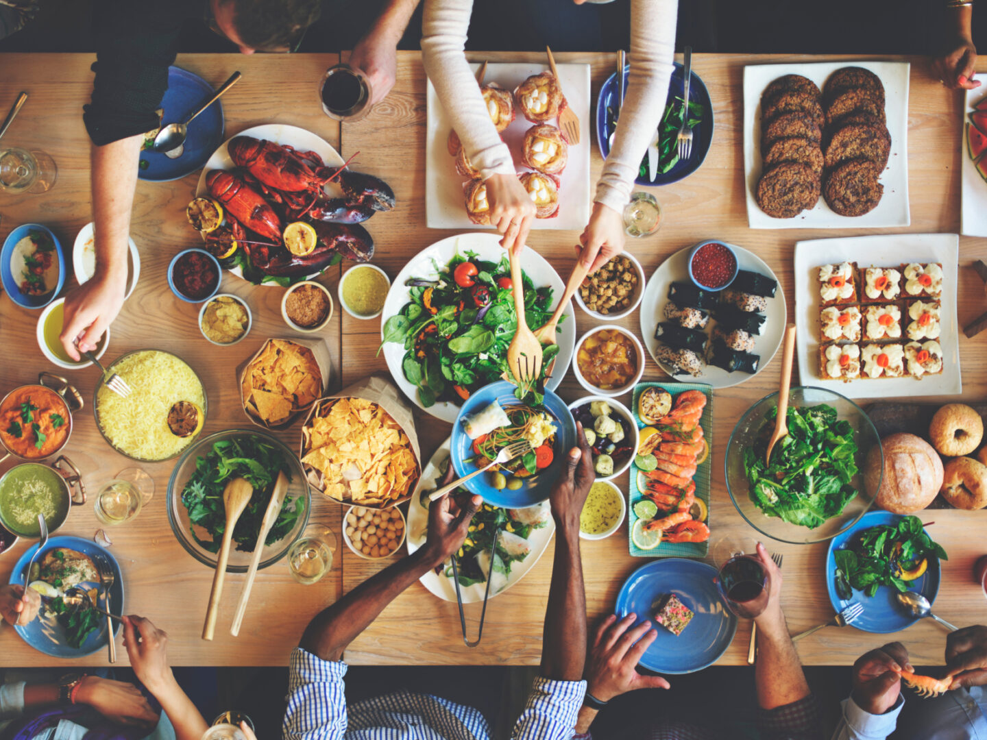 Friends sharing a meal over a table with lots of different food dishes - Food Testing Services